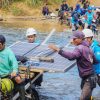Petugas-PLN-bersama-warga-bahu-membahu-membawa-panel-surya-melintasi-sungai